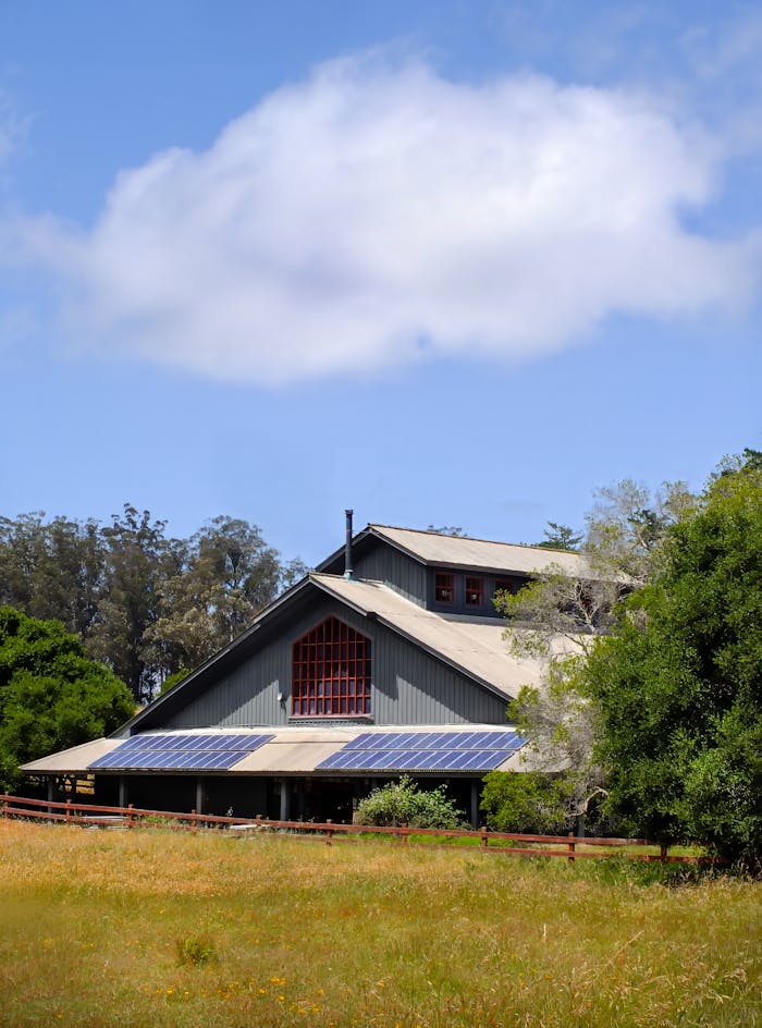 Rustic barn with solar panels amidst a lush rural landscape, highlighting sustainable agriculture.