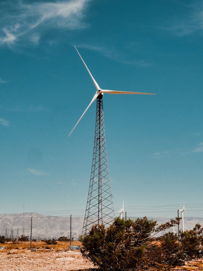 A solitary wind turbine stands tall in a sunny desert setting, symbolizing renewable energy.